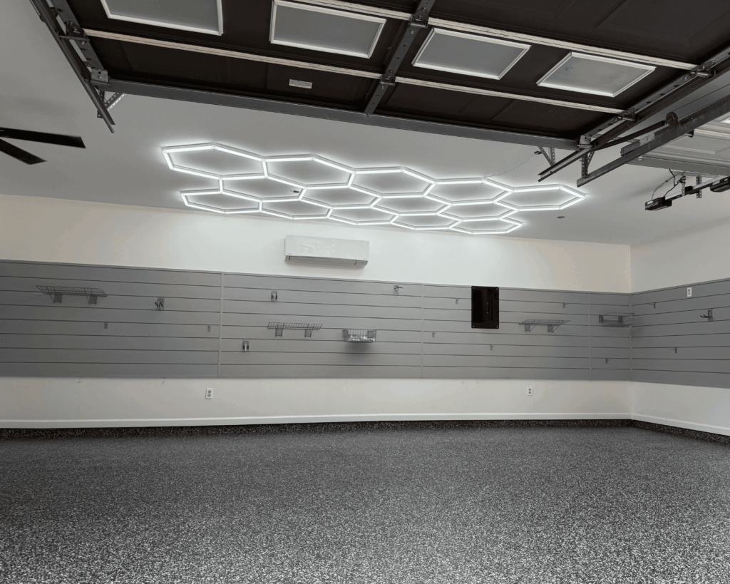 a garage renovation in progress with new slat walls, hex lights, and epoxy floors. garage lighting