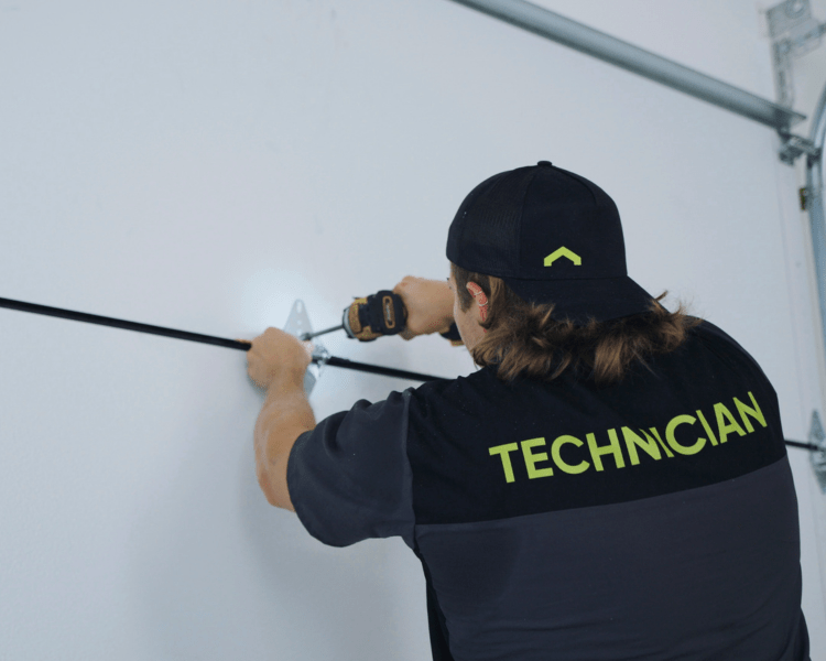 A professional technician installing a hinge on a garage door for a garage renovation project.