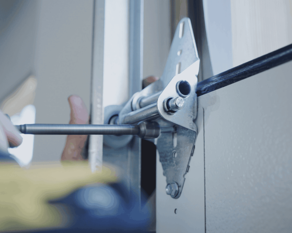 A professional technician working to replace the garage door hinge in a repair job.