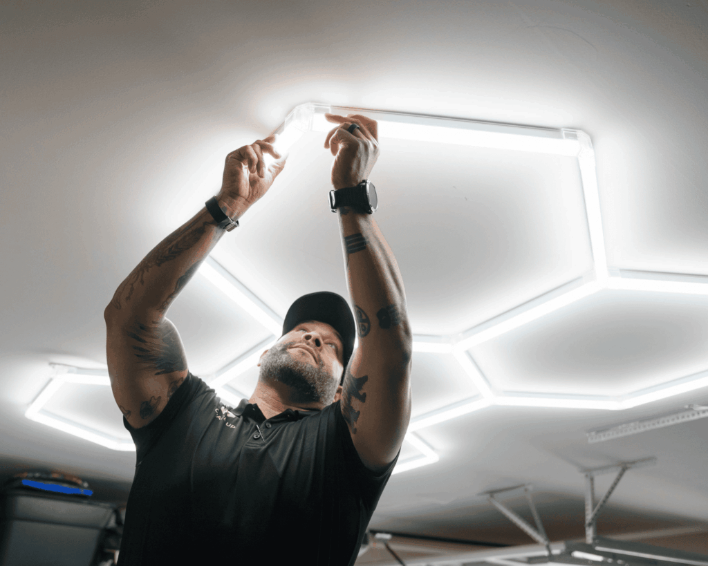 a Garage Up technician installing hex lights onto the ceiling of a garage