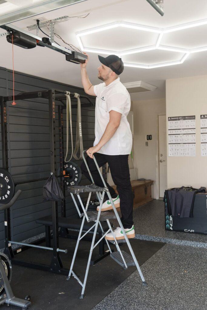 A Garage Up Owner that is on a ladder adjusting the new Garage door system.