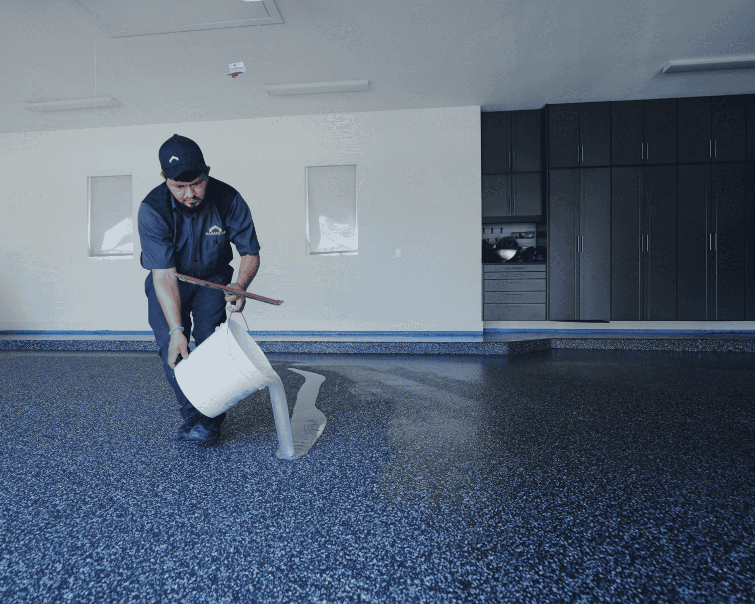a garage up technician applying a sealant coating to the new epoxy flooring