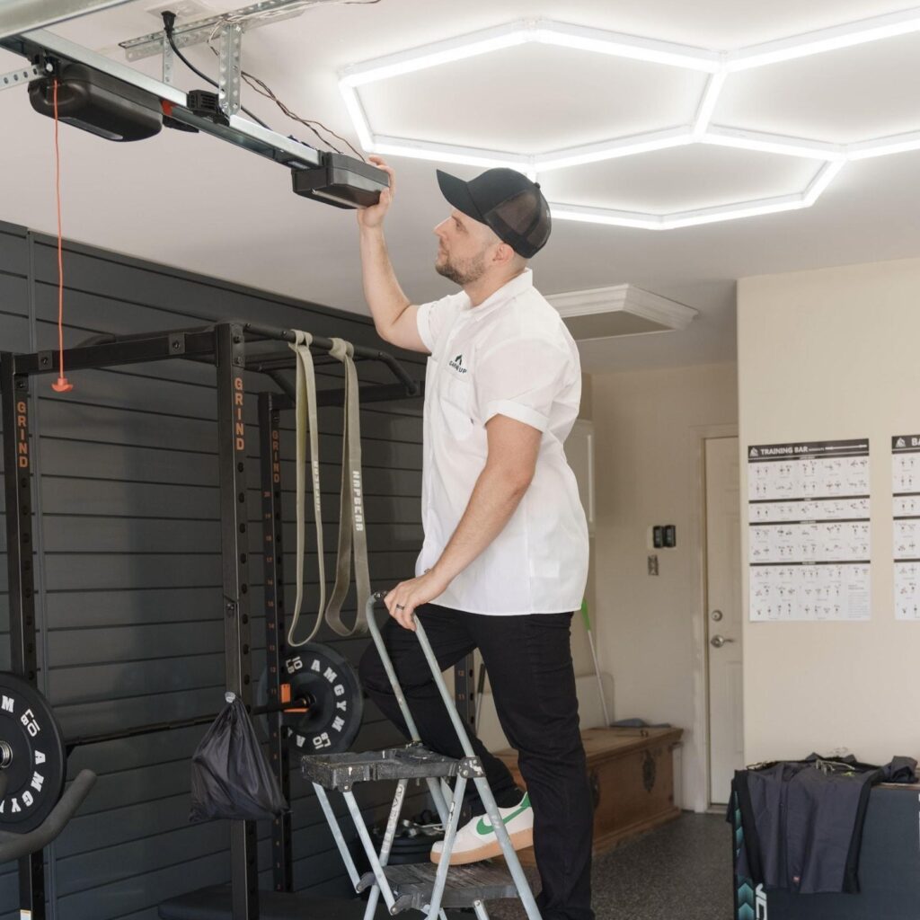 A Garage Up Owner that is on a ladder adjusting the new Garage door system.