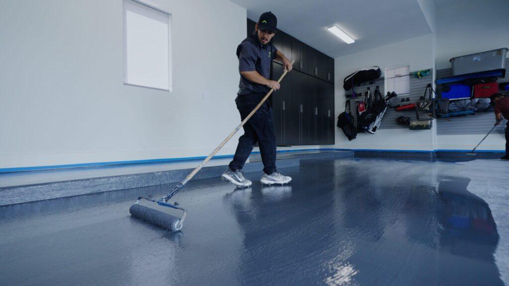 A professional technician installing epoxy flooring in a garage renovation.