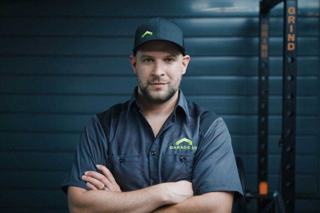 A Garage Up owner posing next to brand new garage flooring and garage doors.