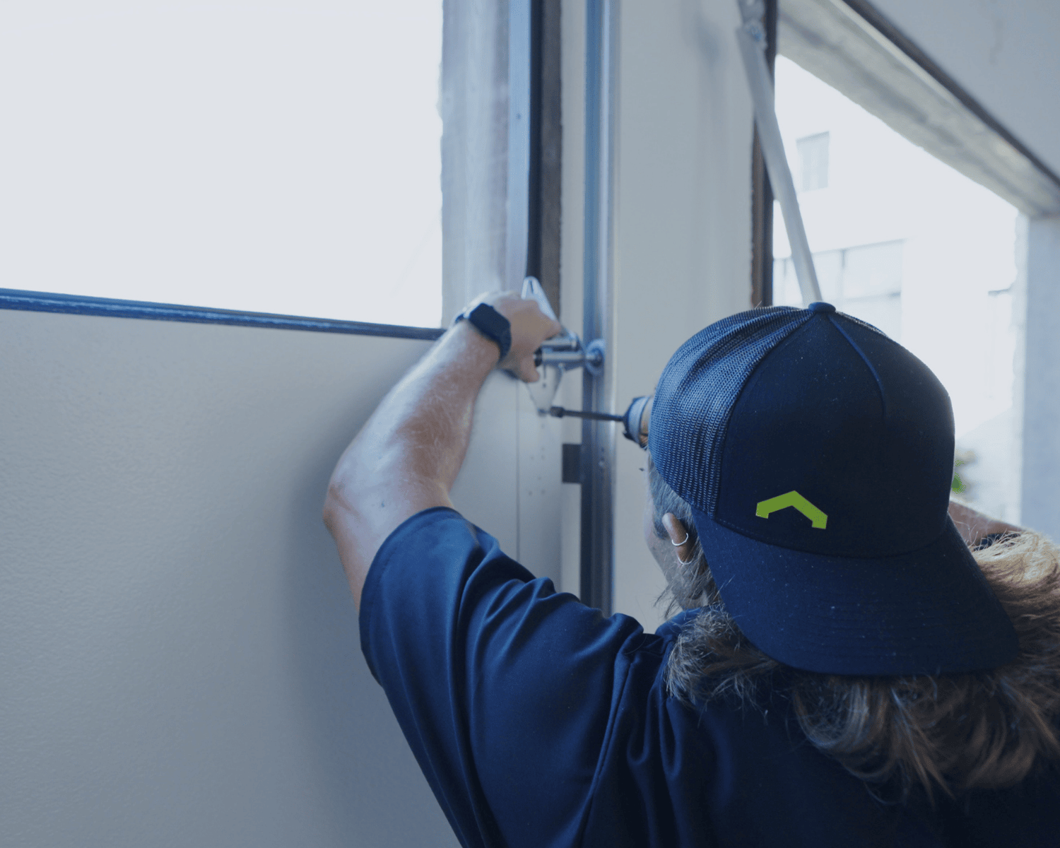 A professional technician installing a hinge on a new garage door.