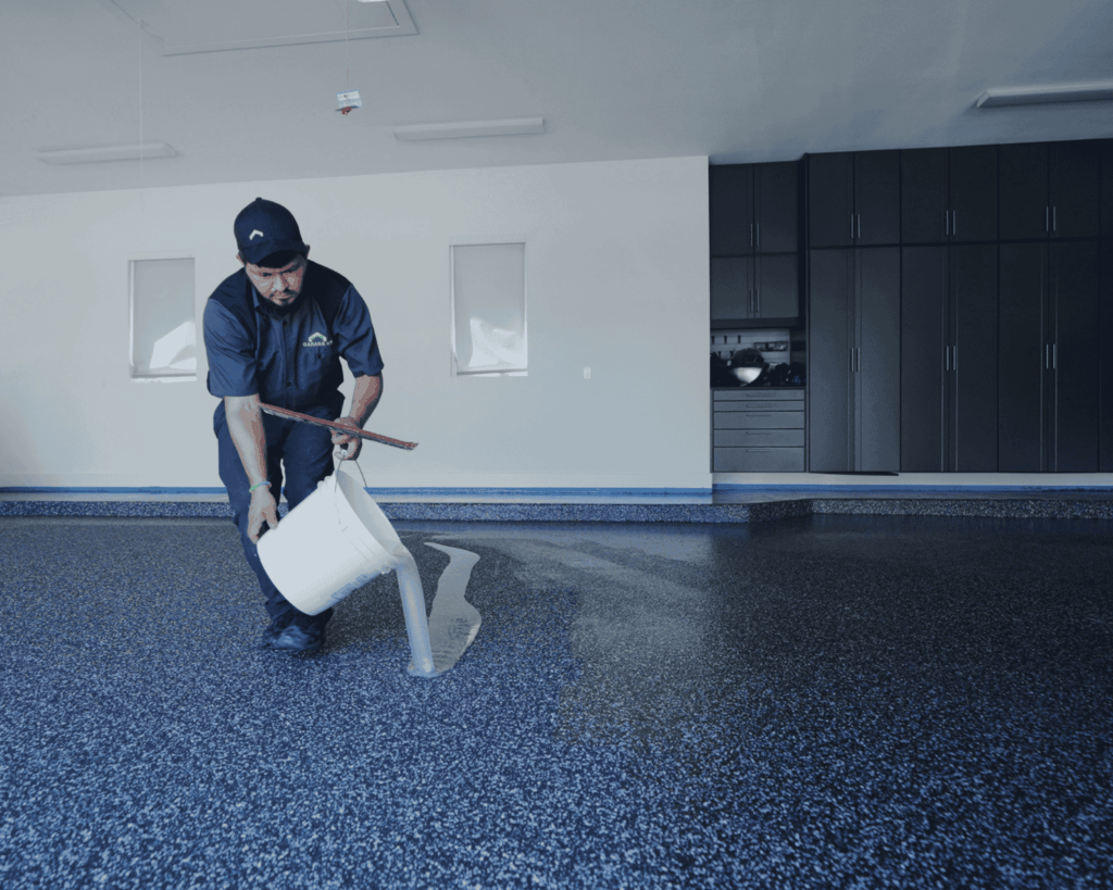 a garage up technician applying a sealant coating to the new epoxy flooring