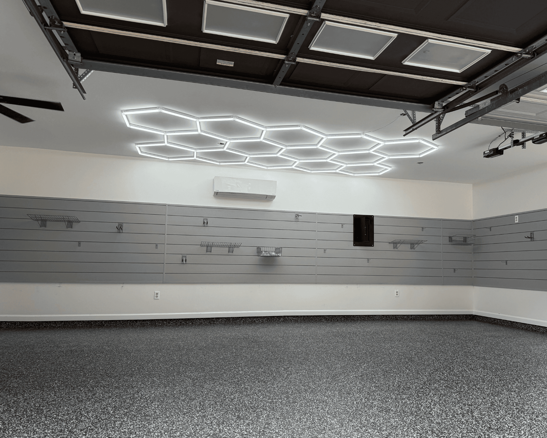 a garage renovation project with new slat walls, hex lights, and epoxy floors. garage extension.