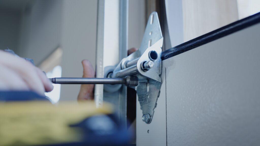a close up of a garage up technician installing a bracket onto a garage door - garage contractor