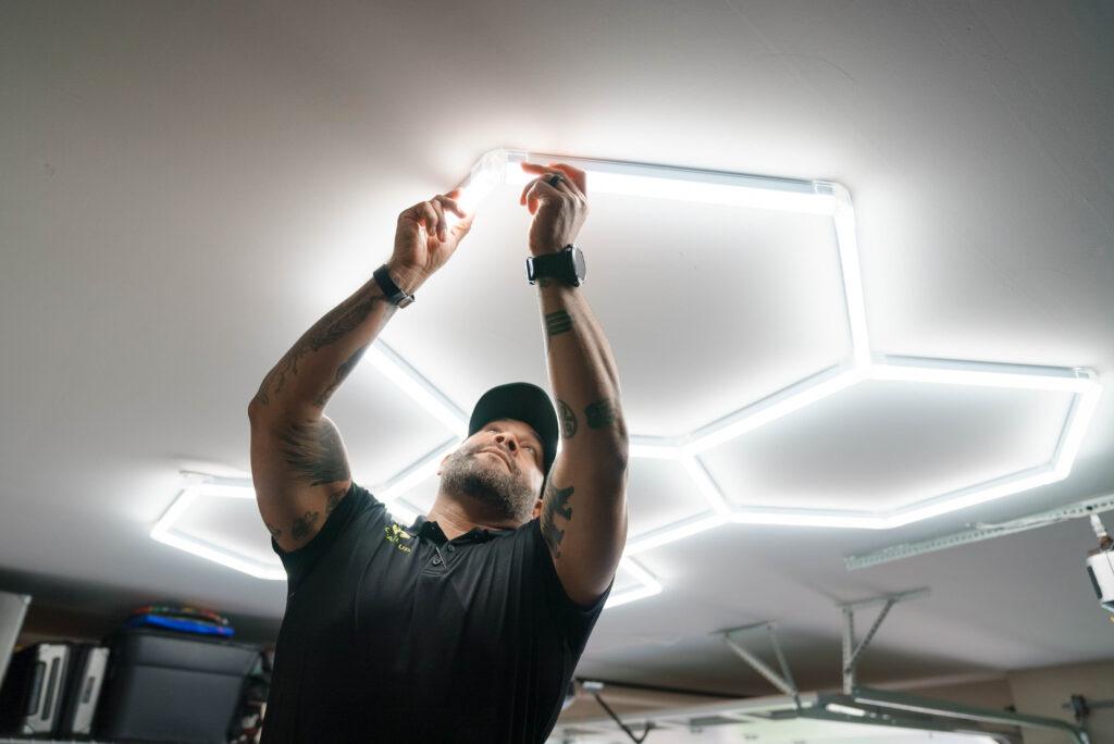 A Garage Up technician installing hexagon lights onto a garage ceiling