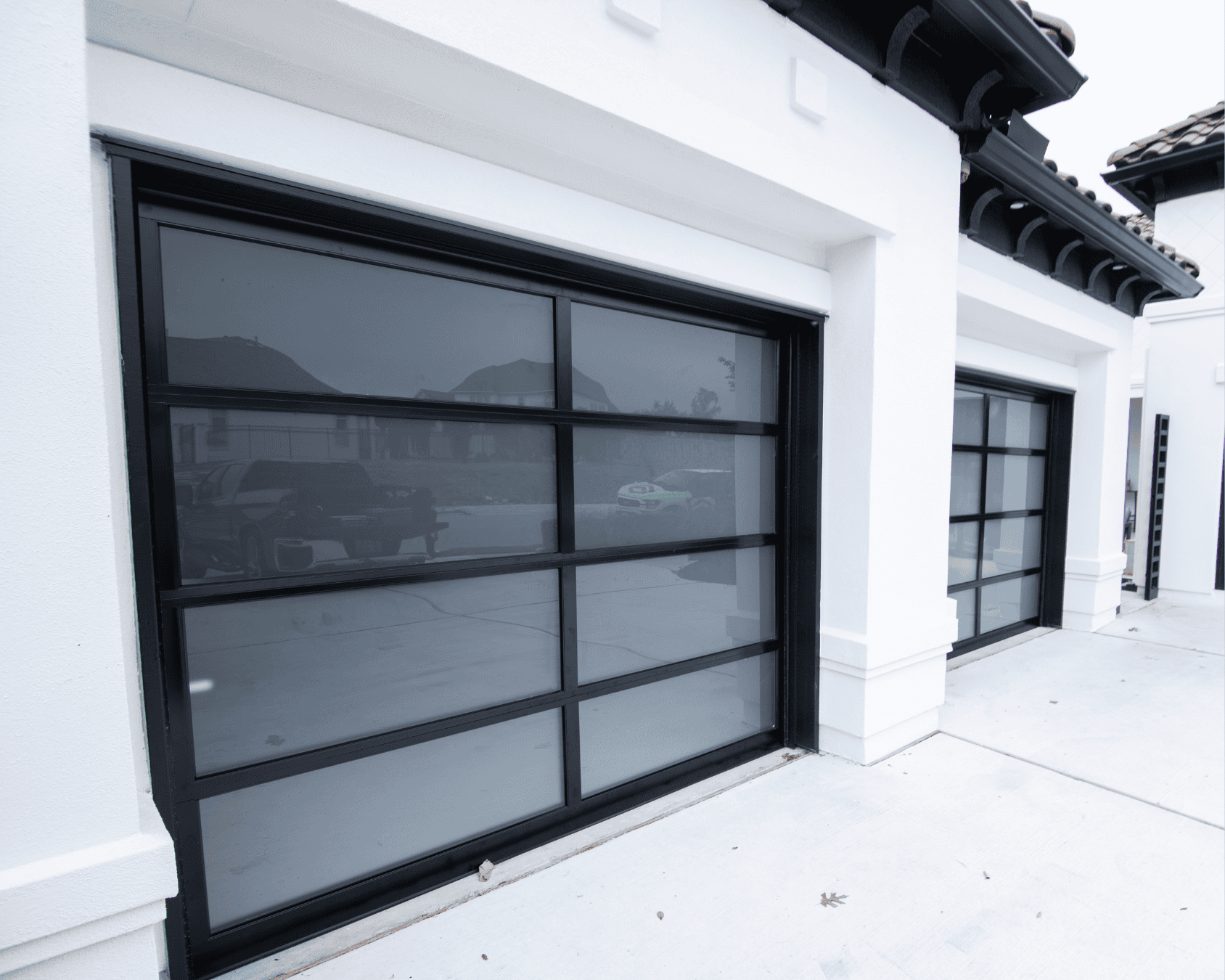 two single-car black full view garage doors installed into a white residential home