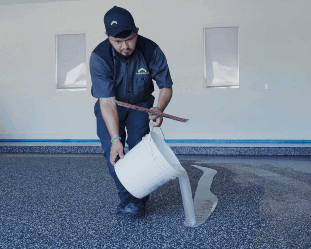 a garage up technician applying resin to an epoxy floor