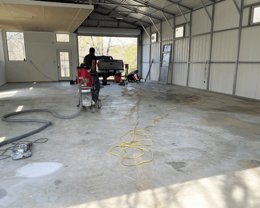 a garage up employee using a large buffer to prepare a floor for an epoxy floor install